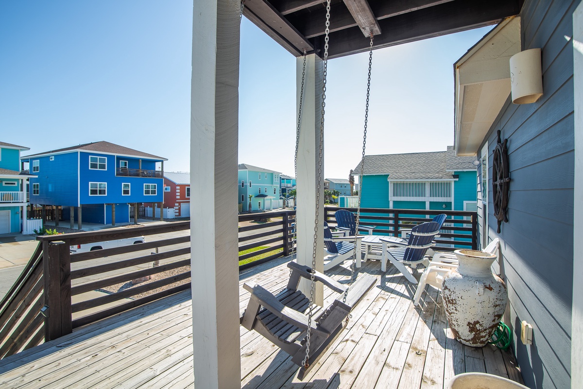 Relax on your private deck with porch swing, dining table, and colorful beach house views in this charming coastal getaway.