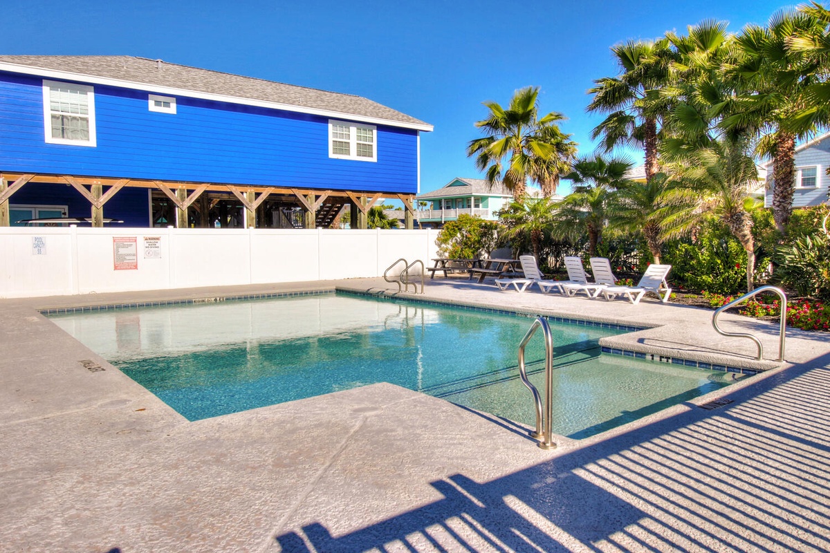 Dive into crystal-clear waters surrounded by tropical palms and colorful beachside architecture in this inviting community pool area.