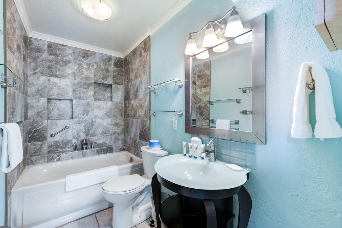 Unwind in your stylish bathroom with natural stone tiles, modern fixtures, and plush towels waiting for your arrival.