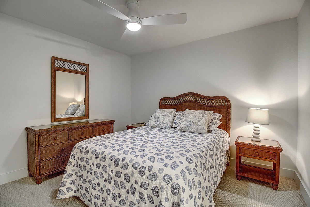 Unwind in your peaceful bedroom with tropical rattan furnishings, soft patterned linens, and a gentle ceiling fan for ultimate comfort.