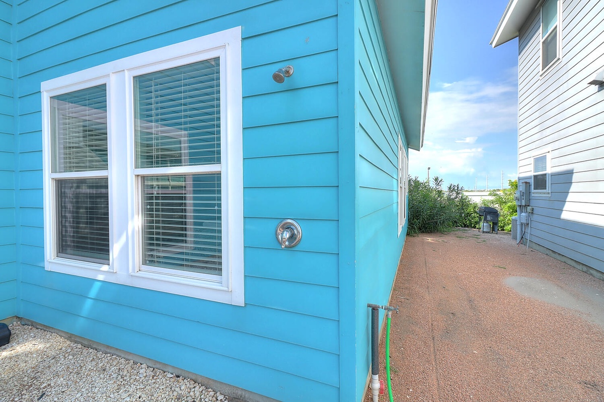 Bright turquoise coastal cottage exterior with neighboring properties in a charming beachside community.