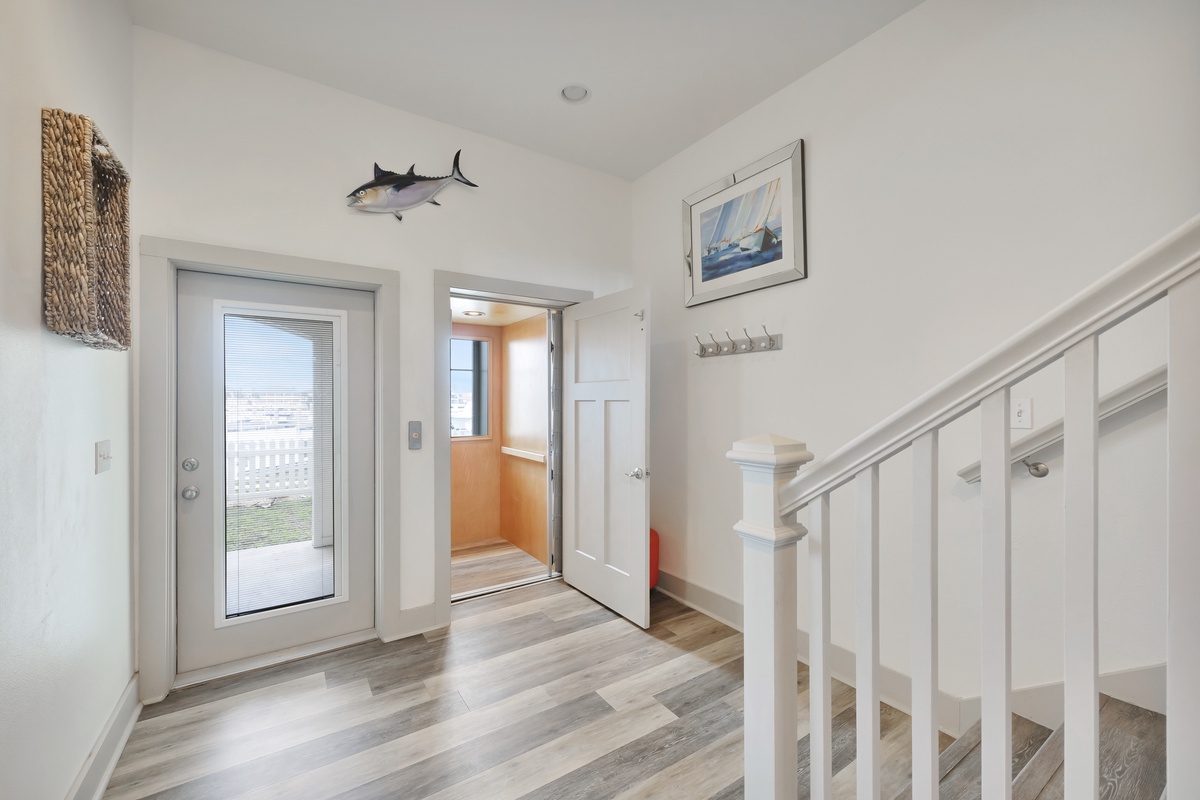 Step into your bright coastal entryway featuring nautical touches, a convenient elevator, and modern hardwood floors that set the tone for your perfect seaside getaway.