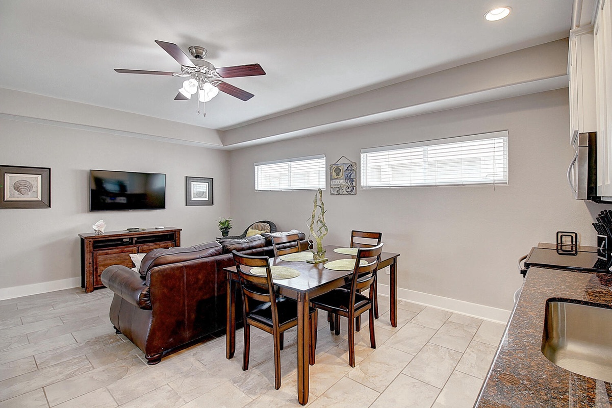 Relax in your spacious open-concept living space with comfortable leather seating, elegant dining for four, and modern entertainment setup.