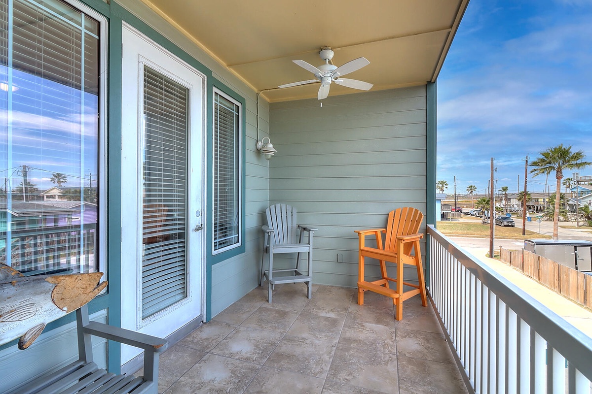 Unwind on your private covered balcony with colorful Adirondack chairs and ceiling fan, perfect for morning coffee or evening relaxation.