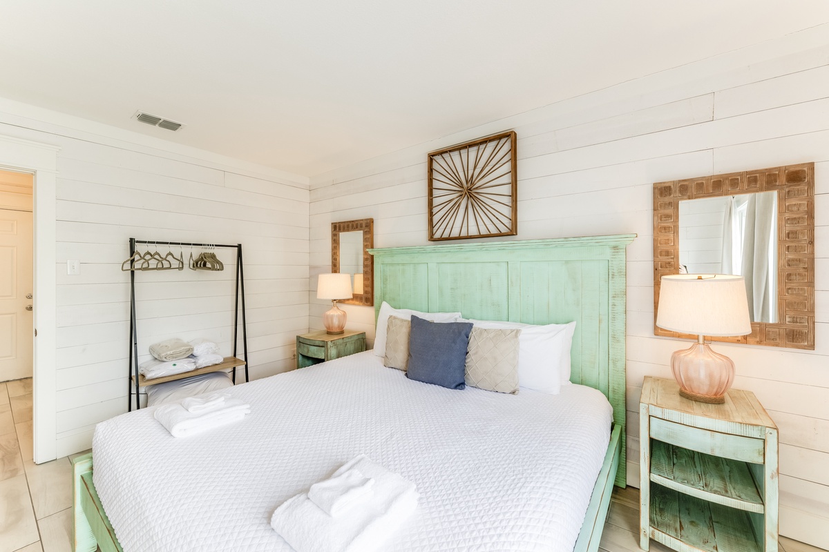 Drift off to sleep in this coastal-inspired bedroom with its charming mint headboard and crisp white shiplap walls. Soft natural light and beachy accents make this your perfect seaside retreat.
