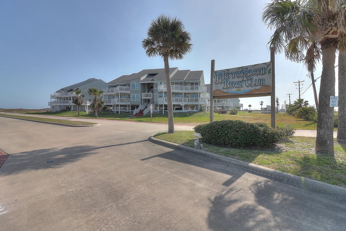 Mustang Island Beach Club entrance welcomes visitors to this coastal property with tropical palm trees and beachside accommodations.