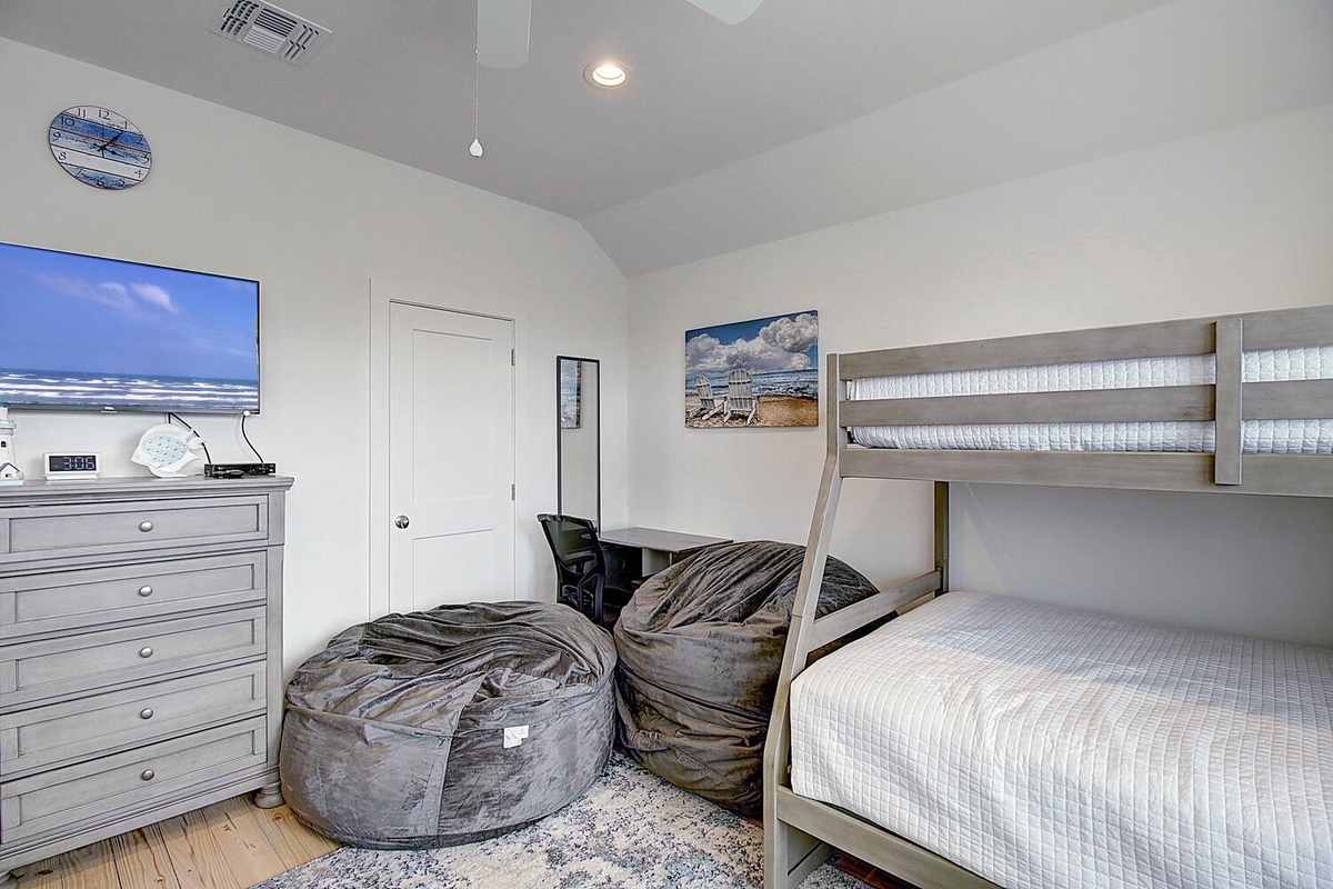 Your kids will love this playful bedroom with comfy bunk beds, bean bags, and beach-themed artwork creating the perfect coastal retreat.