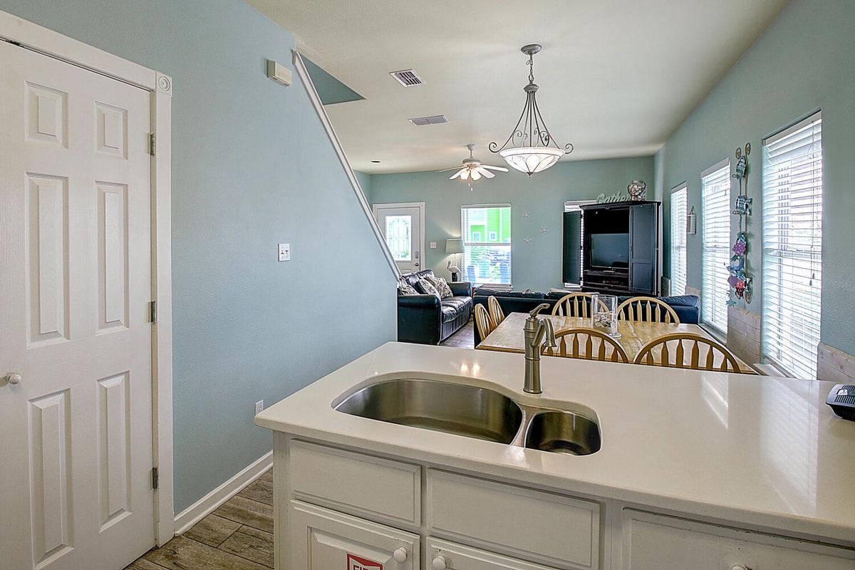 Your open kitchen flows seamlessly into the bright living space, where soft blue walls and natural light create a welcoming atmosphere for your stay.