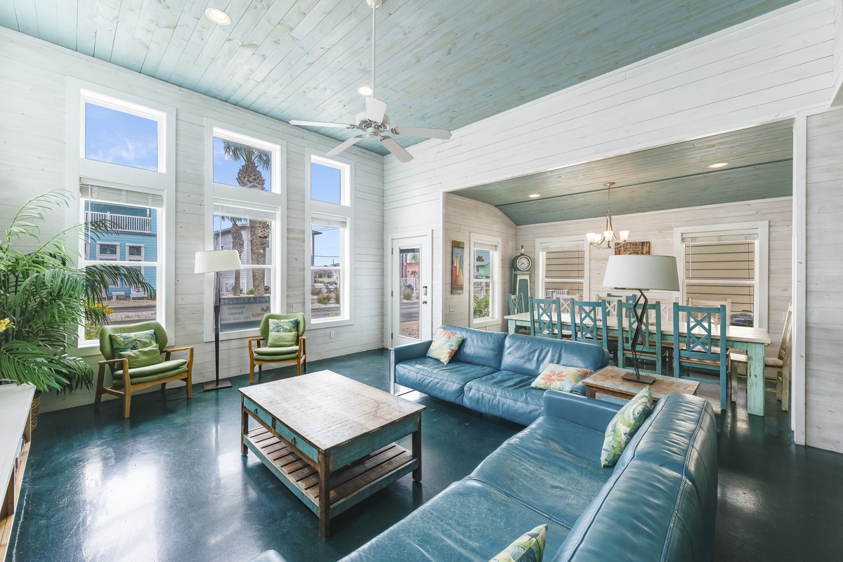 Relax in your bright coastal living room, where ocean blues meet weathered whites and tropical palms peek through windows.