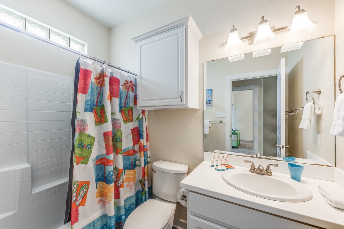 Your bright bathroom features a cheerful shower curtain and vanity with mirror, perfect for freshening up after beach days.