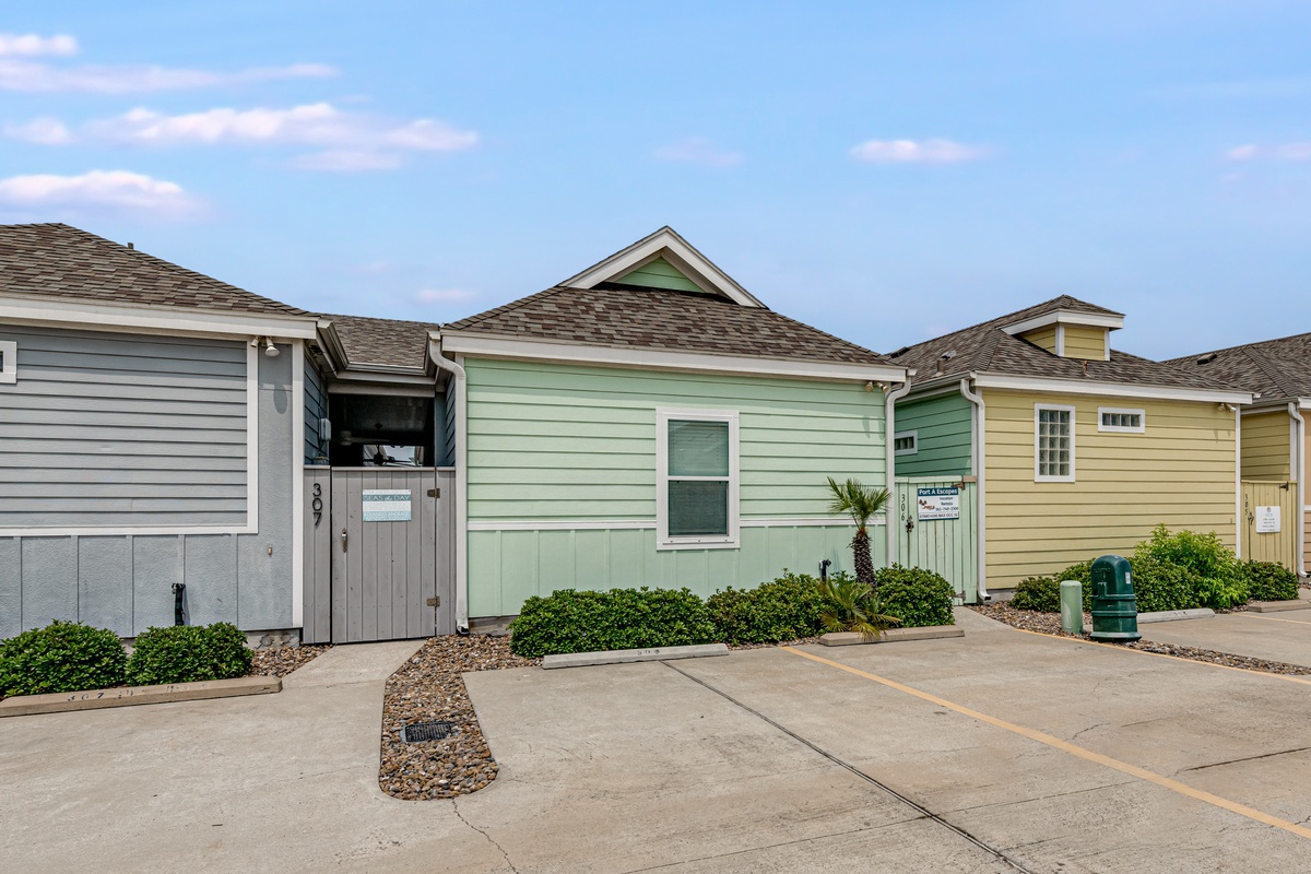 Charming coastal cottages with colorful exteriors and convenient parking create a welcoming beachside retreat.
