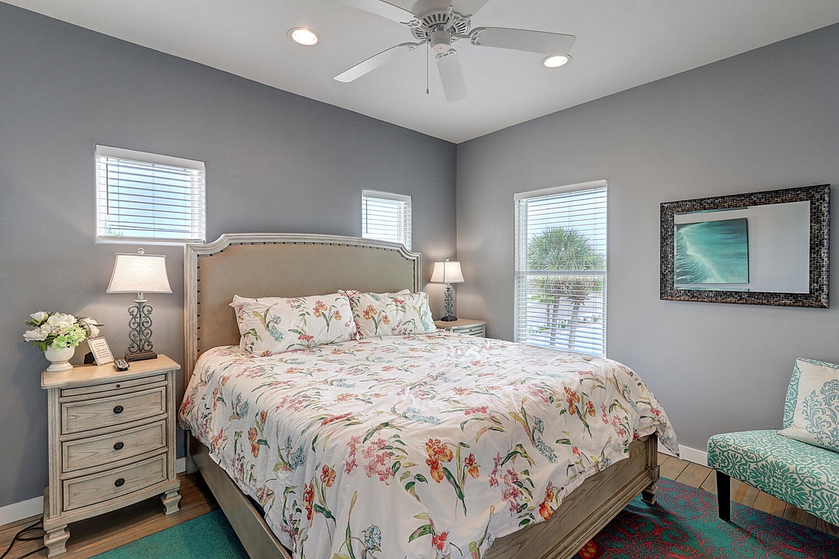 Rest peacefully in this coastal-inspired bedroom with soft floral linens and a gentle ceiling fan breeze.