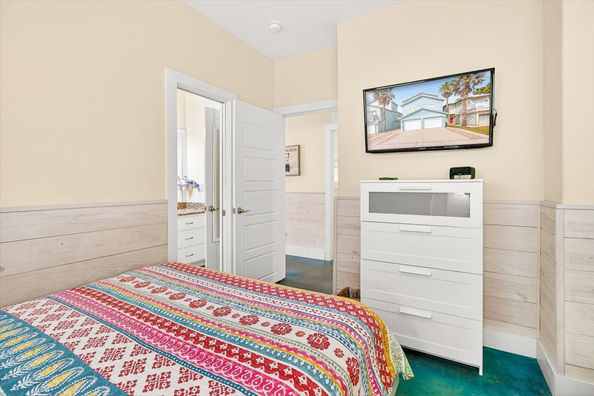 Relax in your cozy bedroom featuring a comfortable bed, flat-screen TV, and ample storage space for all your vacation essentials.