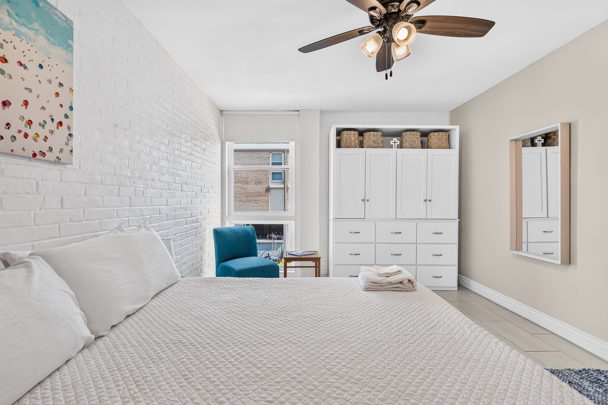 Slip into fresh linens and enjoy the ceiling fan's gentle breeze. Your private retreat features a bright accent wall, cozy reading nook, and plenty of storage to keep your space serene and clutter-free.