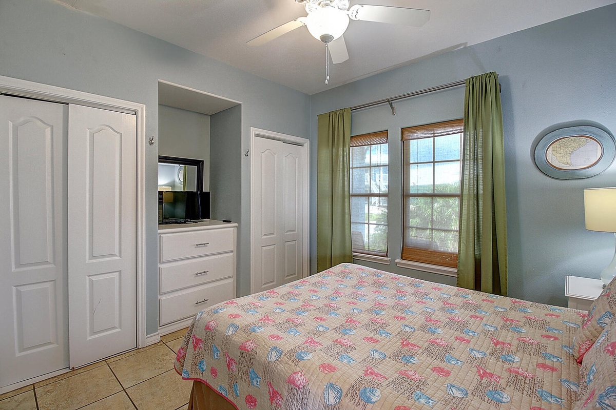 Your peaceful bedroom features soft blue walls, a colorful quilt, and natural light streaming through the window.