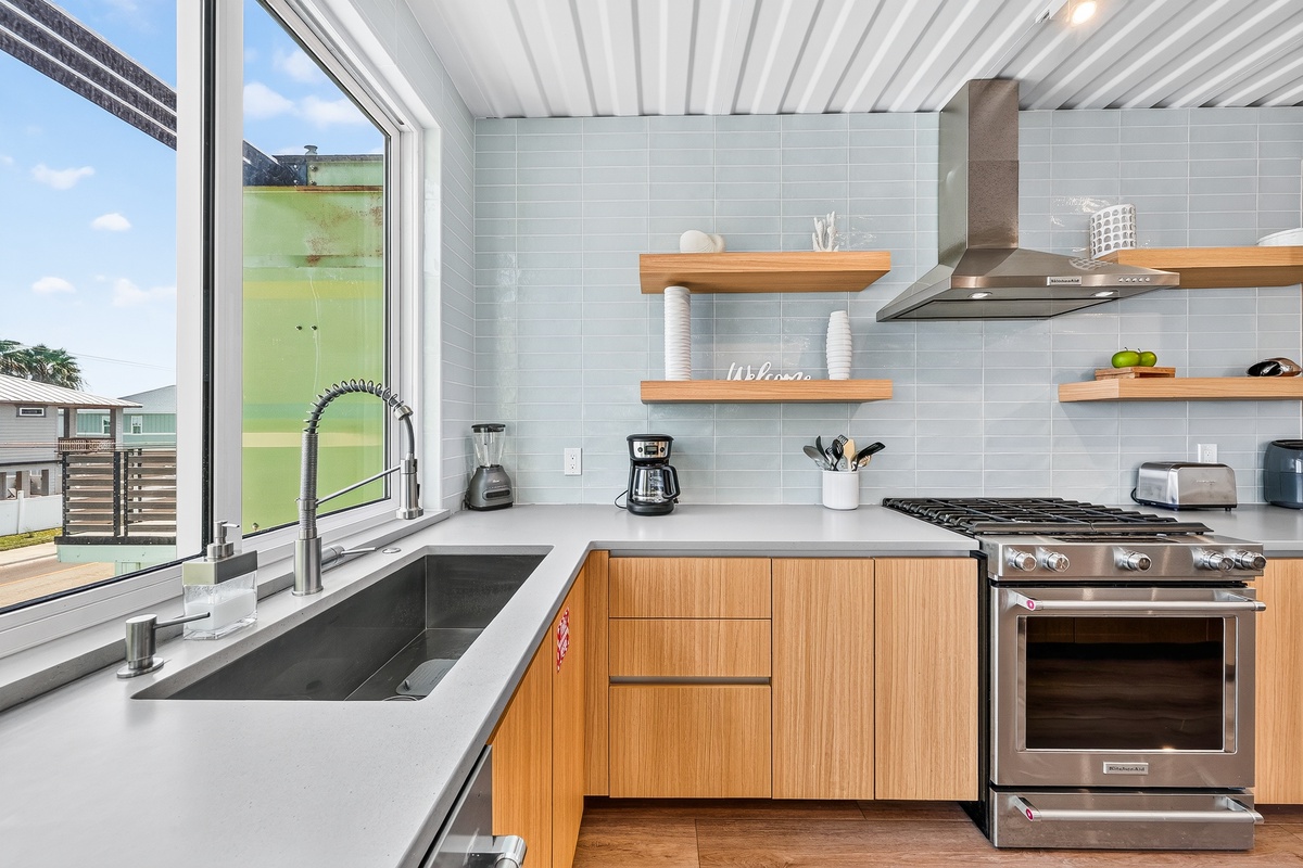 A sleek, modern kitchen awaits with natural light streaming through large windows. Cook your favorite meals using professional appliances while enjoying open shelving and plenty of counter space for meal prep.