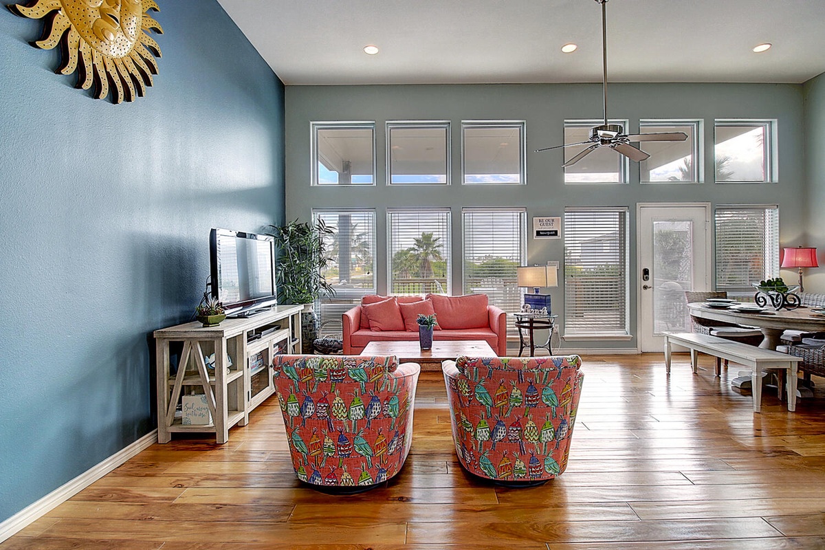 Sink into colorful swivel chairs while soaking up natural light from floor-to-ceiling windows in this vibrant living space.