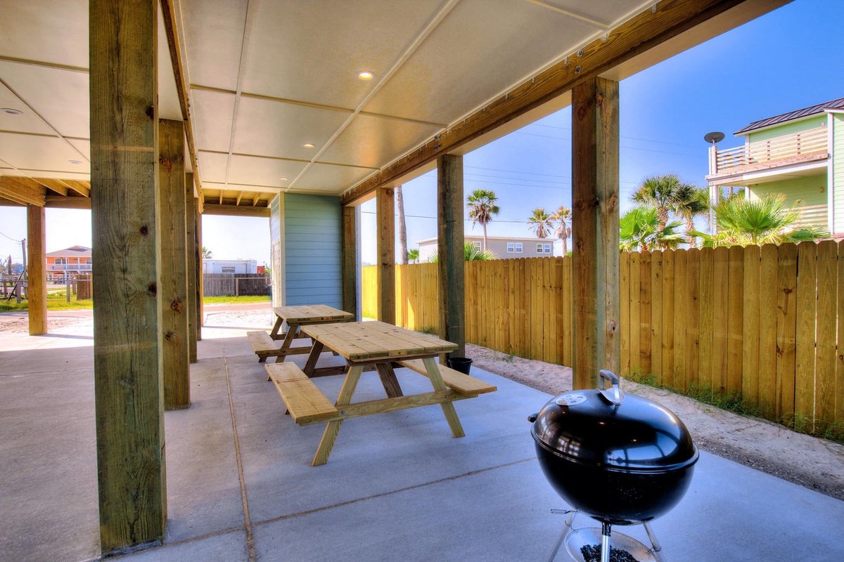 Relax under your covered patio with a picnic table and BBQ grill, perfect for outdoor dining while enjoying tropical palm tree views.