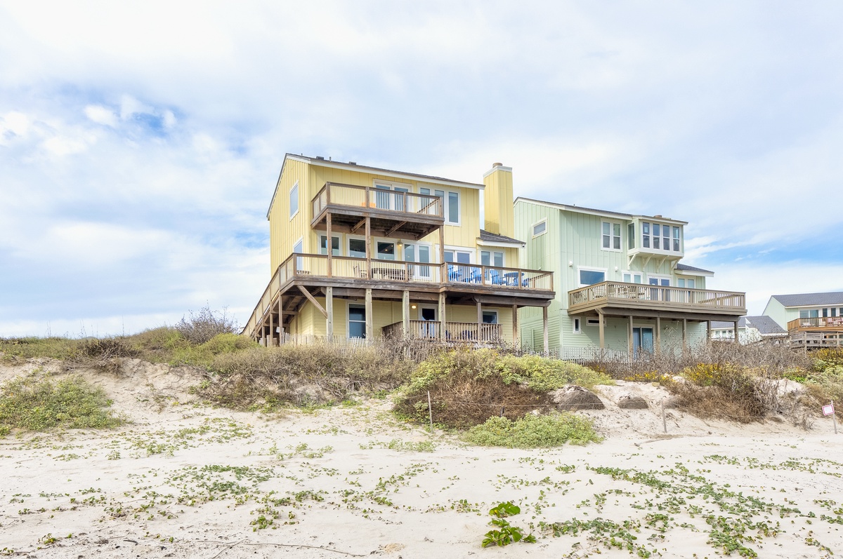 Beachfront vacation homes featuring multi-level decks and direct beach access along sandy coastline.