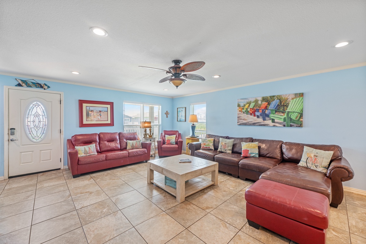 Gather with your group in this spacious living room featuring plush leather seating, coastal artwork, and a ceiling fan to keep you comfortable.