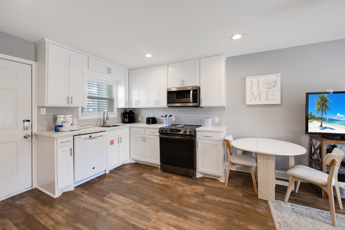 Your modern kitchen welcomes you with crisp white cabinets, stainless appliances, and cozy dining nook—perfect for morning coffee or family meals.