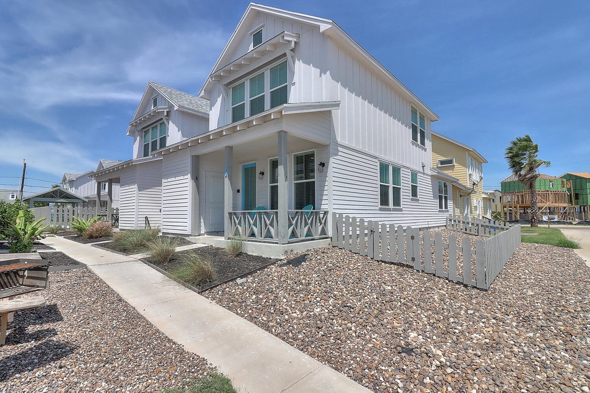 Charming coastal cottage with white picket fence and decorative porch railings in a peaceful beachside neighborhood.