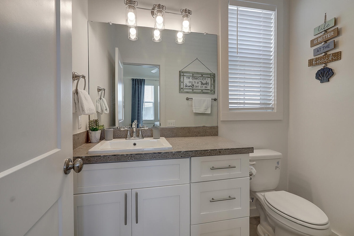 Refresh in your private bathroom with modern vanity, granite countertops, and coastal-themed decor creating a serene retreat.