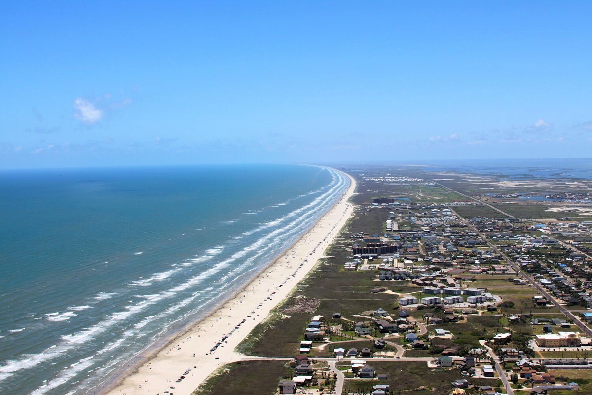 Aerial view showcasing miles of pristine coastline with sandy beaches stretching along the turquoise ocean waters and nearby residential areas.