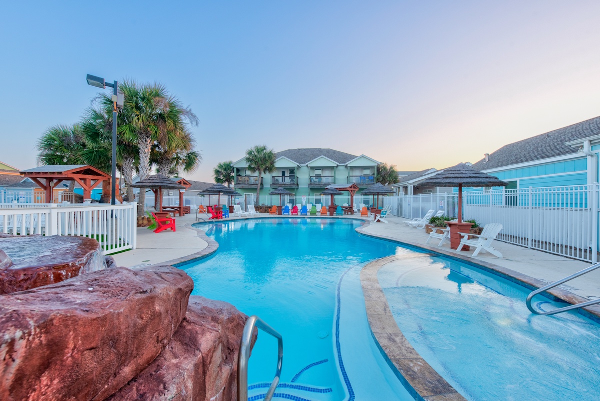 Dive into crystal-clear waters surrounded by colorful beach chairs and swaying palms—your perfect poolside paradise awaits.