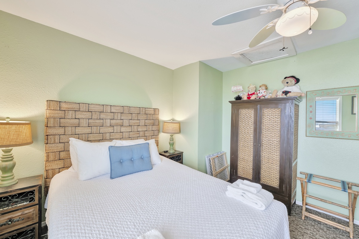 Drift off to sleep in this peaceful bedroom with its calming green walls, plush bedding, and gentle ceiling fan creating your perfect retreat.