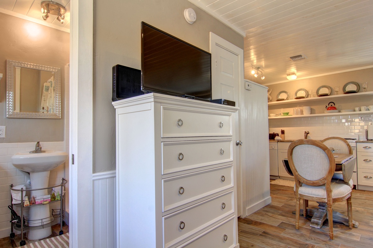 Your charming space features a large flat-screen TV on elegant white storage, plus a cozy dining nook with vintage-style seating.