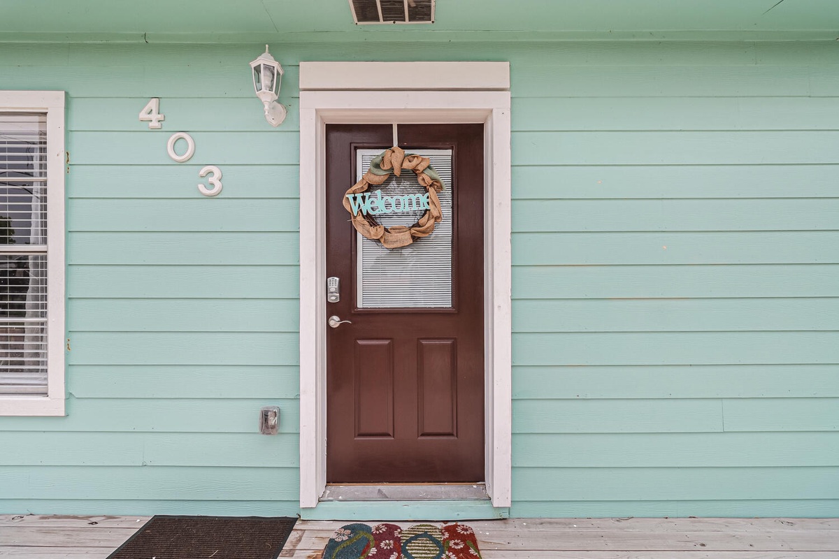 A charming mint green entrance with welcoming wreath marks your arrival at unit 403.