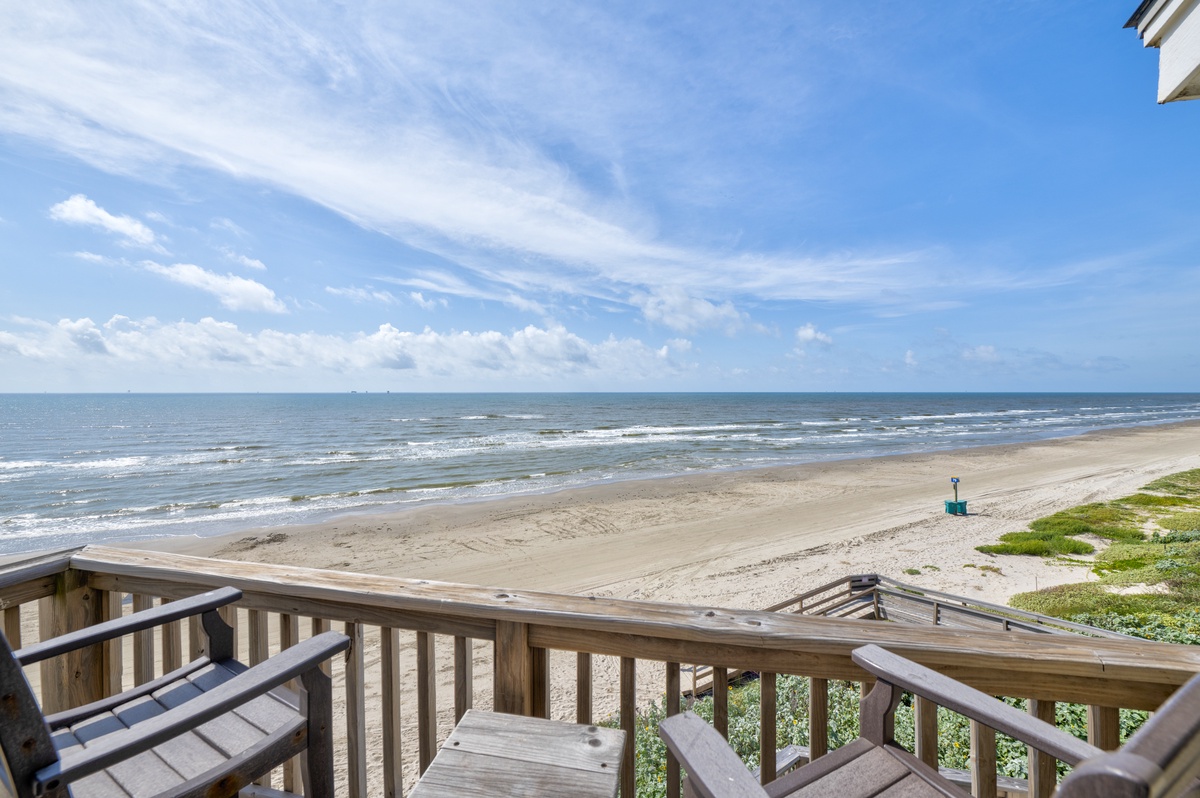 This beachfront property offers direct access to pristine sandy shores and sweeping ocean views beneath a vast, cloud-streaked sky.