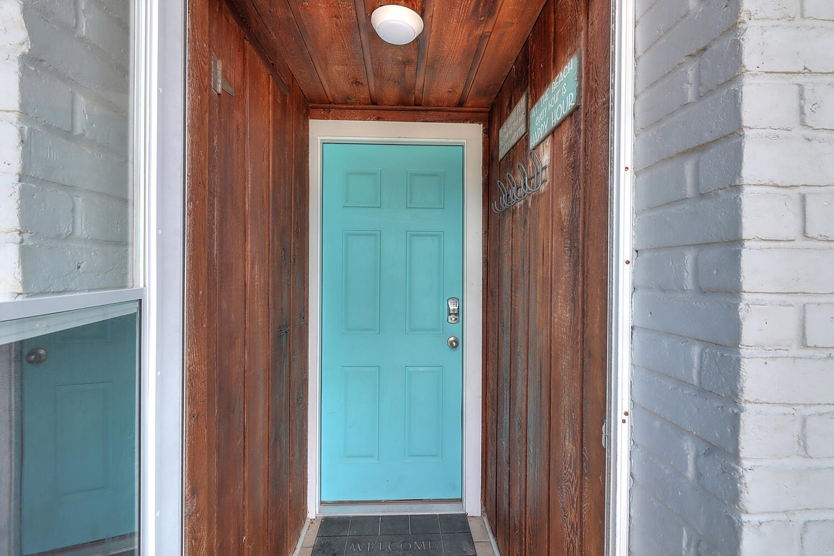 Charming entrance featuring a bright turquoise door and warm wood ceiling, creating a welcoming first impression.