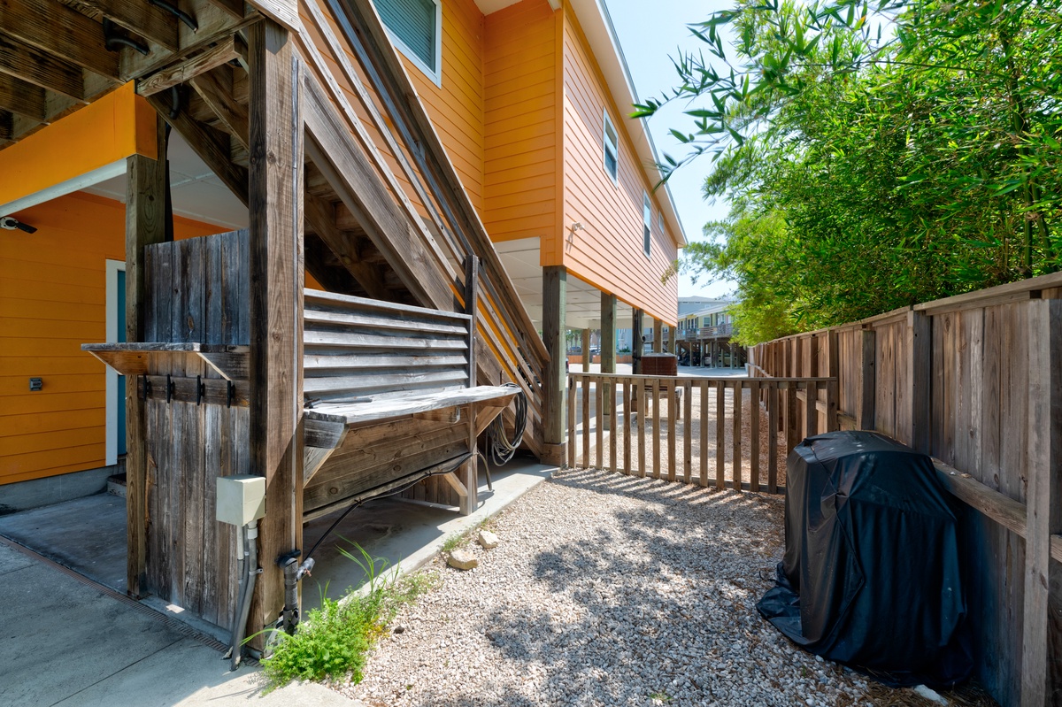 Modern vacation home features vibrant orange siding and rustic wooden staircase leading to upper-level accommodations.