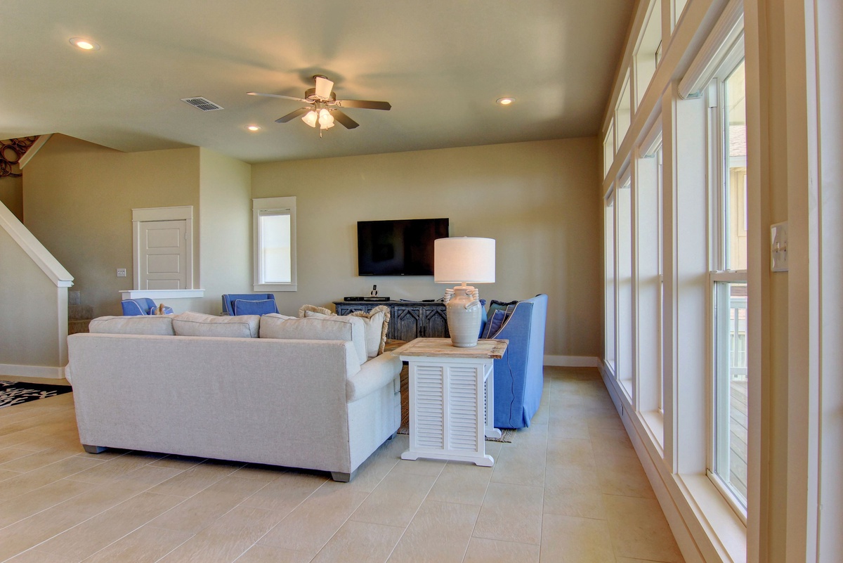 Relax in your spacious living room with comfortable seating, modern TV, and beautiful natural light streaming through large windows.