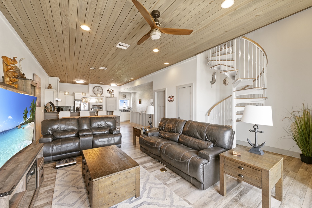 Unwind in your open-plan living space featuring warm wood ceilings, leather seating, and a stunning spiral staircase.