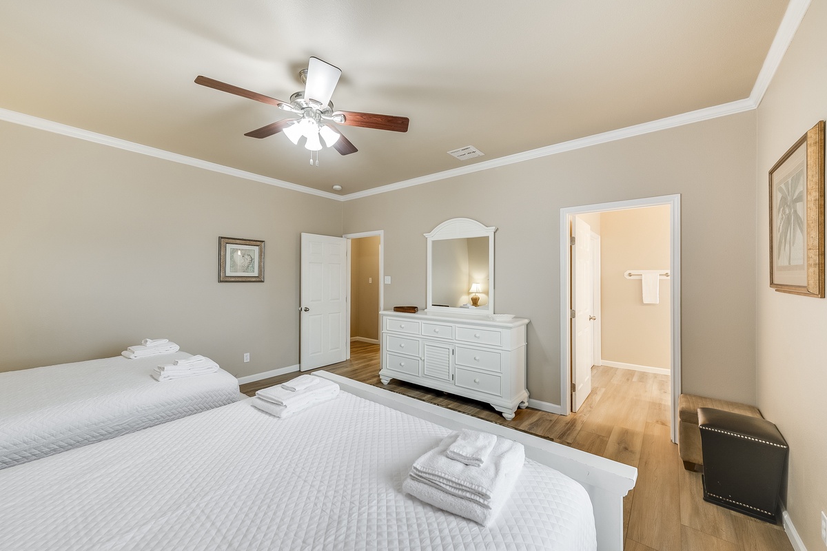 Relax in your serene bedroom with crisp white linens, warm hardwood floors, and a gentle ceiling fan for perfect comfort.