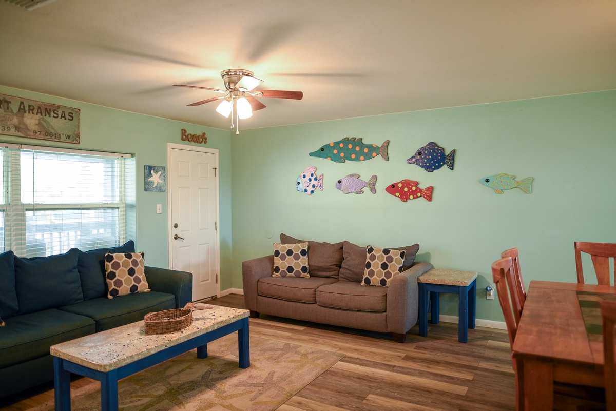 Unwind in your cheerful living space with playful fish decor, cozy seating, and bright coastal vibes perfect for family gatherings.