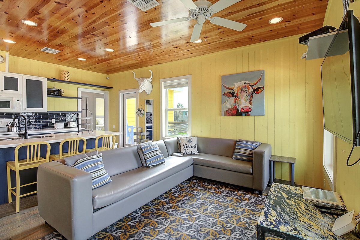 Relax in your cheerful open-concept space featuring rustic wood ceilings, cozy sectional seating, and a fully equipped kitchen perfect for your getaway.