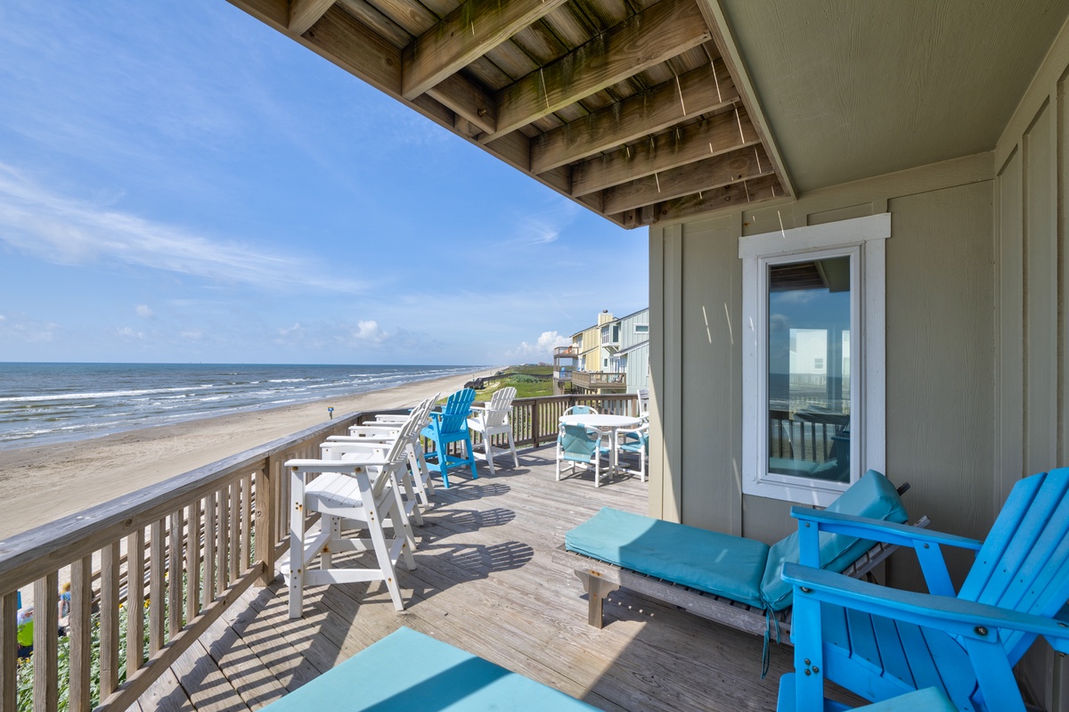Direct beachfront property featuring a spacious deck with coastal views, comfortable seating, and easy sandy shore access along the shoreline.