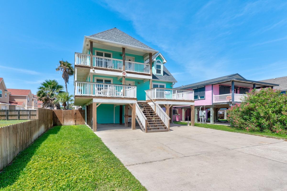Bright turquoise beach house with spacious balconies and convenient parking in a colorful coastal neighborhood.