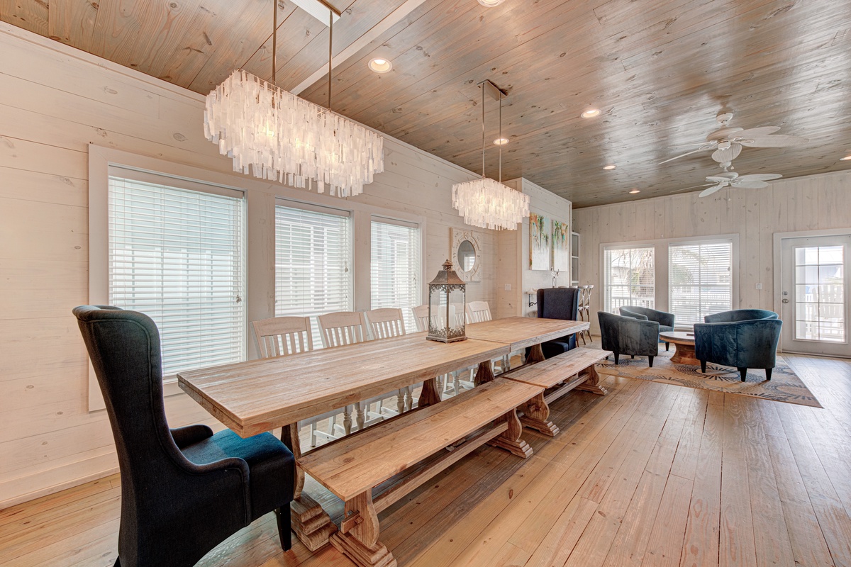 Gather around this stunning farmhouse dining table beneath elegant chandeliers, where wood ceilings and walls create your perfect retreat.