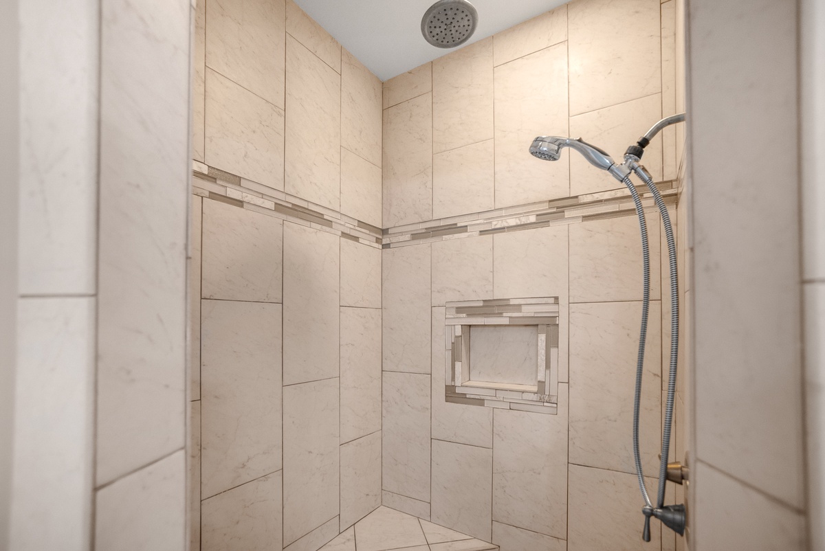Step into your spacious walk-in shower featuring elegant stone tiles and dual shower heads for the ultimate relaxing experience.