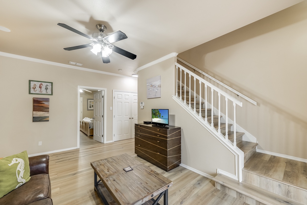 Relax in your spacious living room featuring gleaming hardwood floors, a ceiling fan for comfort, and entertainment center for cozy evenings.