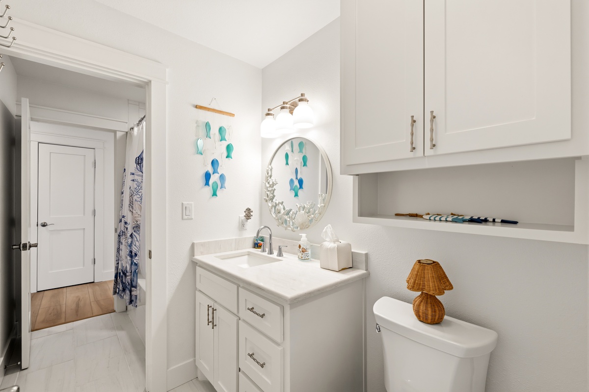 Step into your bright, coastal-inspired bathroom where turquoise fish art and nautical touches create a relaxing seaside feel. Fresh white cabinetry and open shelving keep your essentials within easy reach.