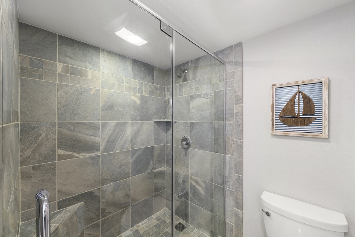 Step into your modern bathroom featuring a spacious walk-in shower with beautiful stone-look tiles and glass doors.