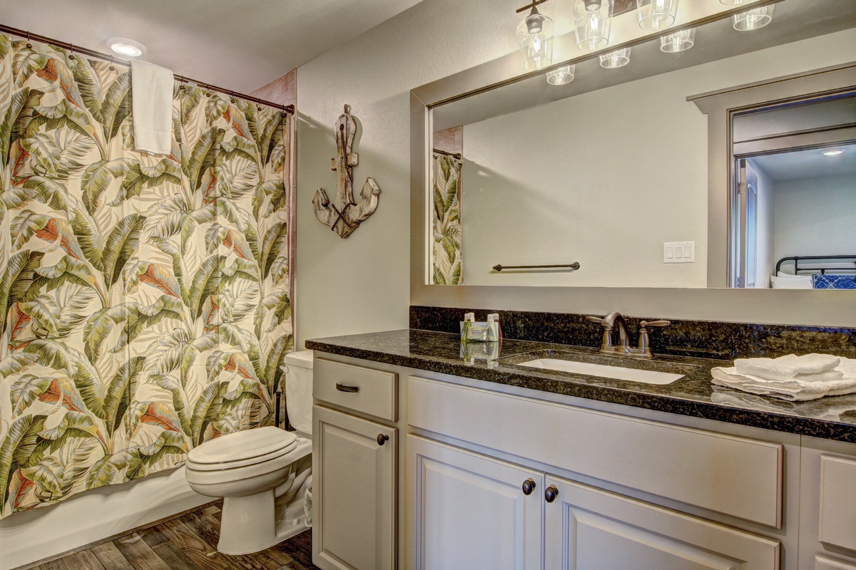 Unwind in your tropical-themed bathroom with marble countertops, fresh towels, and charming nautical decor creating a serene coastal escape.