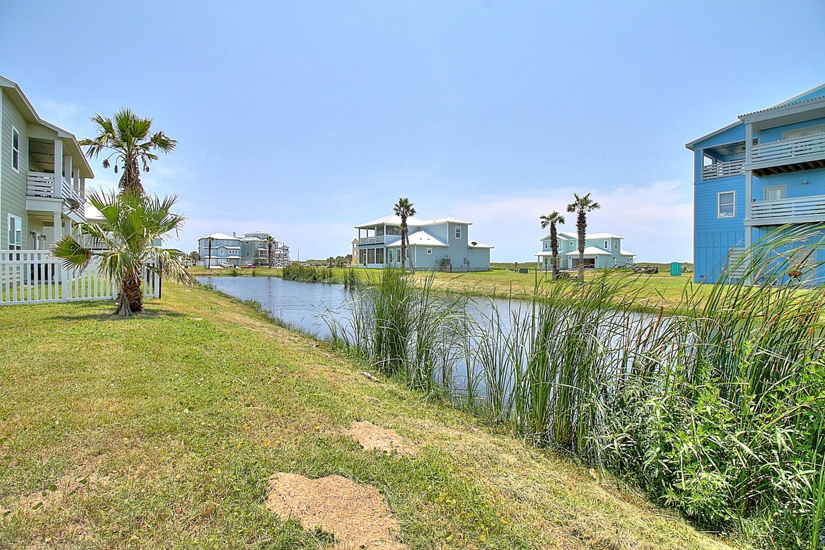 Waterfront community with colorful coastal homes overlooking peaceful lagoon waters surrounded by lush tropical vegetation.