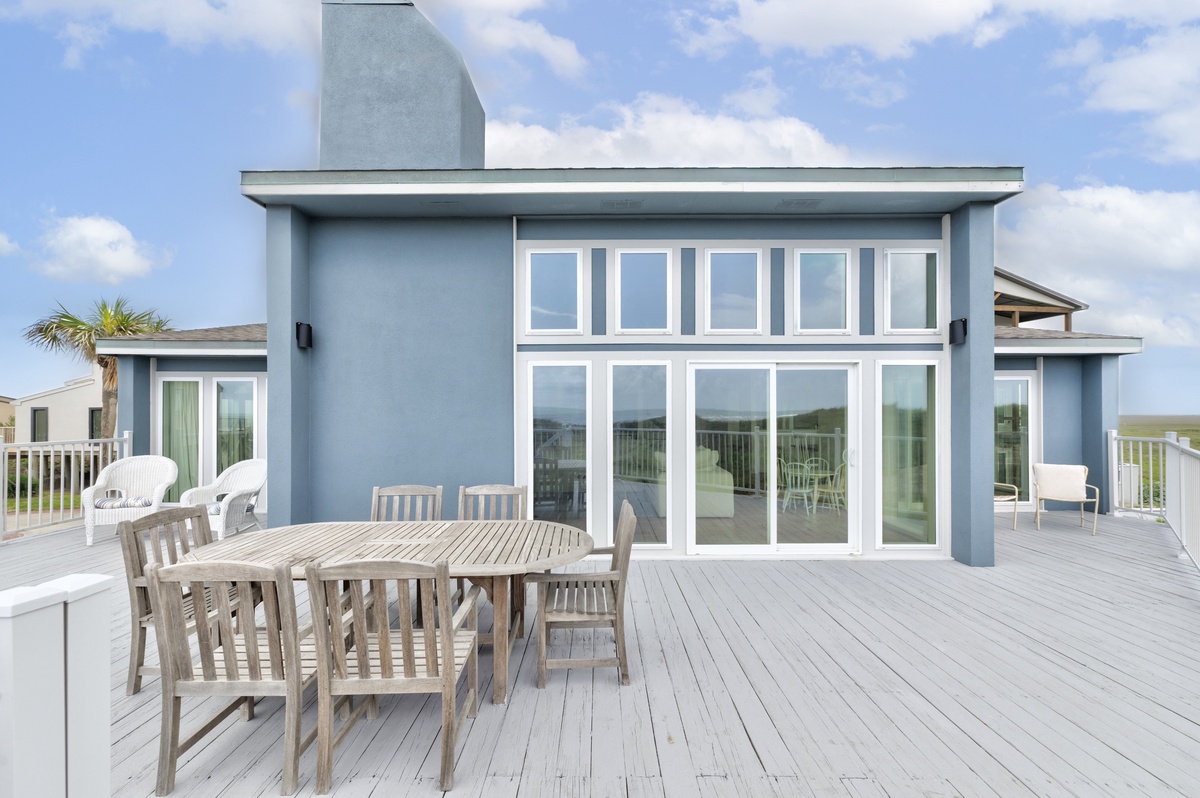 Modern beachfront property featuring expansive deck space and floor-to-ceiling windows overlooking coastal surroundings.